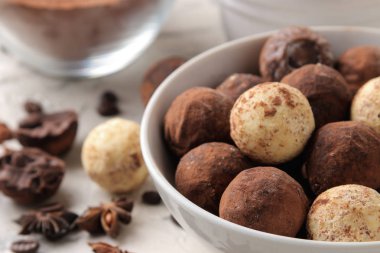 çeşitli çikolatalar. Şeker topları çikolata hafif bir beton zemin üzerine farklı türde. kakao, yıldız anason ve kahve çekirdekleri