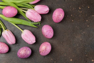 Paskalya. Pembe Paskalya yumurta ve karanlık bir arka plan üzerinde çiçekler. Mutlu paskalyalar. tatil. Üstten Görünüm.
