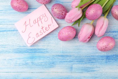 Paskalya. Pembe Paskalya yumurta ve mavi ahşap bir masa üzerinde çiçekler. Mutlu paskalyalar. tatil. Üstten Görünüm