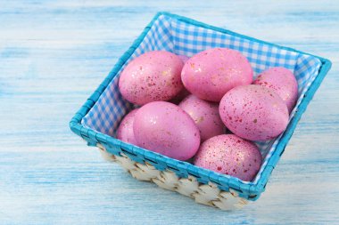Paskalya. Mavi ahşap bir masa üzerinde bir sepette pembe Paskalya yumurtaları. Mutlu paskalyalar. tatil.