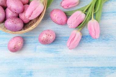 Paskalya. Pembe Paskalya bir sepete yumurta ve mavi ahşap bir masa üzerinde çiçekler. Mutlu paskalyalar. tatil. Üstten Görünüm