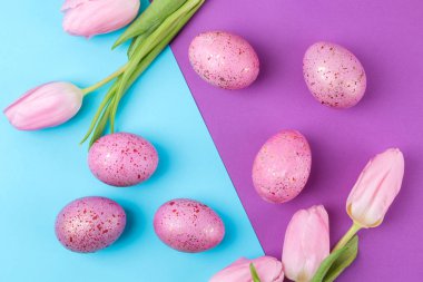 Paskalya. pembe Paskalya yumurta ve trendy Eflatun ve mavi arka plan üzerinde çiçekler. Mutlu paskalyalar. tatil. Yukarıdan görüntülemek.