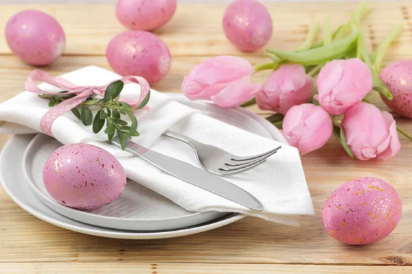 Easter. Easter table setting. Pink Easter eggs and flowers tulips on a natural wooden table. Happy easter. holidays.