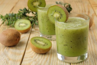 Bir bardak taze kivi dilimleri doğal ahşap bir masa yanında kivi smoothies.