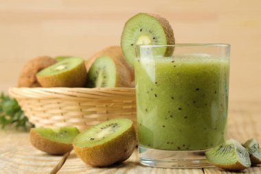 Bir bardak taze kivi dilimleri doğal ahşap bir masa yanında kivi smoothies.