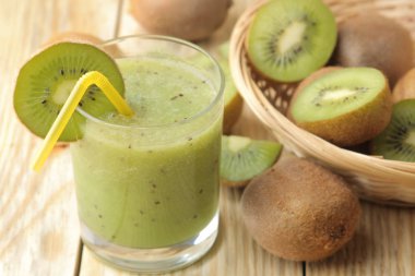 Bir bardak taze kivi dilimleri doğal ahşap bir masa yanında kivi smoothies.