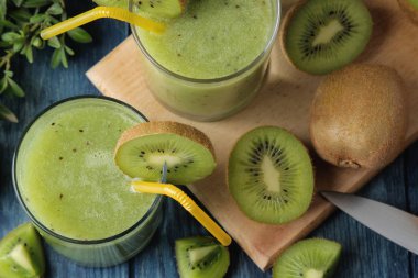 Kivi smoothies bir bardak taze kivi dilimleri üzerinde mavi bir ahşap masa yanında. meyve iç. Üstten Görünüm