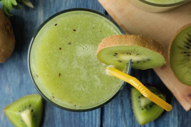 Kivi smoothies bir bardak taze kivi dilimleri üzerinde mavi bir ahşap masa yanında. meyve iç. Üstten Görünüm