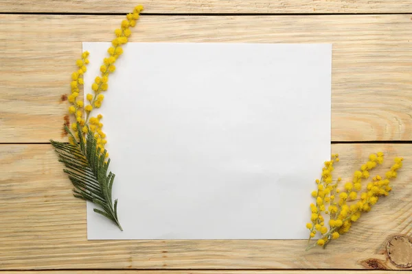 Güzel çiçekler sarı Mimoza ve bir yazıt üzerinde doğal ahşap bir masa boş. Üstten Görünüm