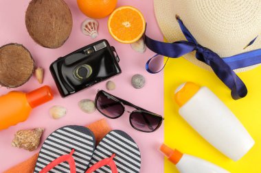 Aksesuar güneş gözlüğü, şapka, kabukları ile yaz, flip flop, parlak sarı ve pembe arka plan üzerinde bir kamera. Üstten Görünüm.