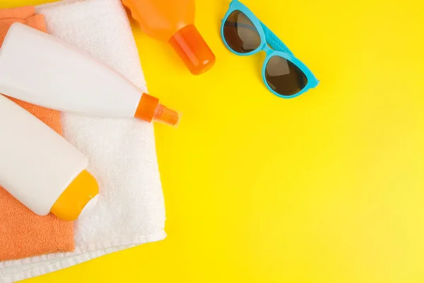 stock image summer accessories. beach accessories. sunscreen and towels on a bright yellow background. top view. space for text