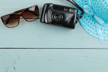 Ahşap mavi bir arka plan üzerinde seyahat kavramı şapka, kamera ve güneş gözlüğü. Üstten Görünüm. metin için yer