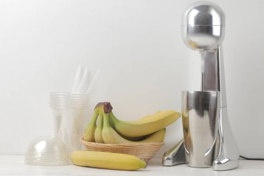 Bir milkshake yapma. Mikser milkshake, tek kullanımlık bardak ve hafif bir arka plan üzerinde muz. boş alan.