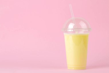 Bir milkshake yapma. bir muz milkshake parlak şık pembe arka plan üzerinde plastik tek kullanımlık bardak. metin için yer