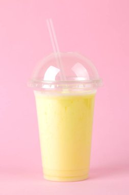 Bir milkshake yapma. parlak bir moda pembe arka plan üzerinde bir muz milkshake ile plastik tek kullanımlık bardak.