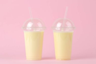 Bir milkshake yapma. parlak bir moda pembe arka plan üzerinde bir muz milkshake ile plastik tek kullanımlık bardak.