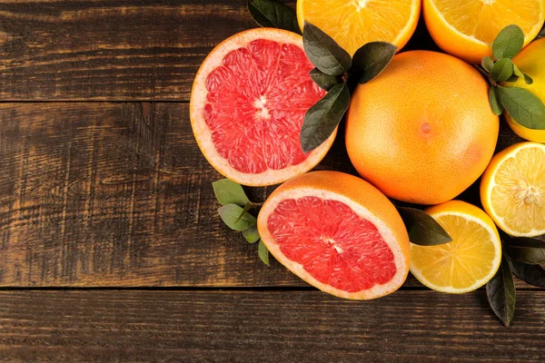 Citrus fruit. Various citrus fruits with leaves of lemon, orange, grapefruit on a brown wooden table. top view