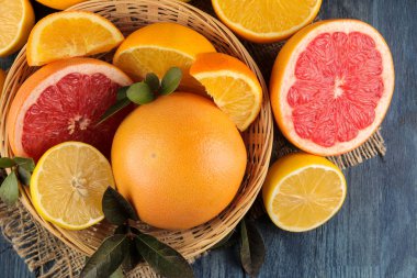 Narenciye meyve. çeşitli narenciye yaprakları limon, portakal, greyfurt, mavi ahşap bir masa üzerinde bir sepet ve portakal suyu ile. Üstten Görünüm