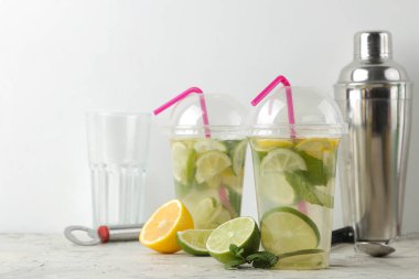 Kokteyl bar aksesuarları üzerinde beton masa lambası ve limon, nane ve limon ile bir plastik bardak Mojito. bir mojito yapmak.
