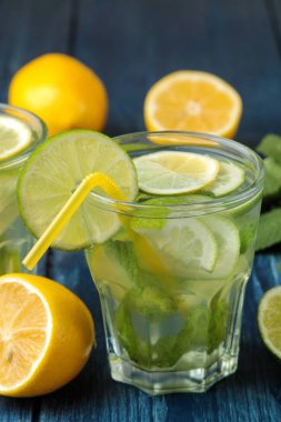 Kokteyl limon, nane ve limon mavi ahşap bir masa üzerinde bir cam bardak Mojito. bir mojito yapmak.