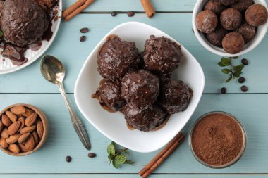 Çikolatalı dondurma ve tarçın çubuğu, kahve çekirdekleri ve badem mavi ahşap arka plan üzerinde sıvı çikolata ile. Üstten Görünüm