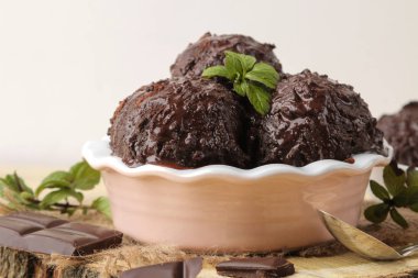 Sıvı çikolata ile Çikolatalı dondurma ve doğal ahşap zemin üzerine nane yaprağı.