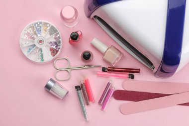Manikür. tırnak cilaları, Uv lambası ve çeşitli aksesuar ve manikür moda pembe bir arka plan üzerinde. Üstten Görünüm