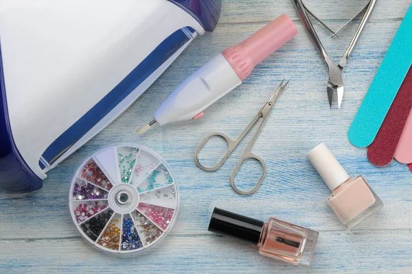 Manicure. nail polishes, UV lamp and various accessories and tools for manicure on a blue wooden table. top view