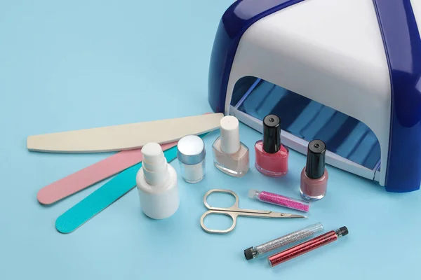 Manicure. nail polishes, UV lamp and various accessories and tools for manicure on a trendy blue background.