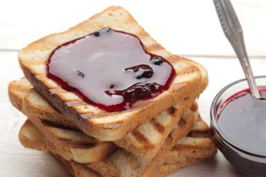 tost reçelli. Beyaz ahşap bir masa üzerinde kırmızı reçel ile kızarmış gevrek tost.