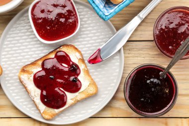 tost reçelli. doğal ahşap bir masa üzerinde kırmızı reçel ile kızarmış gevrek ekmek. Kahvaltı. Üstten Görünüm