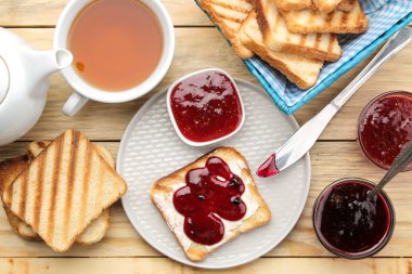 tost reçelli. doğal ahşap bir masa üzerinde kırmızı reçel ile kızarmış gevrek ekmek. Kahvaltı. Üstten Görünüm