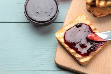 tost reçelli. Mavi ahşap bir masa üzerinde kırmızı reçel ile kızarmış gevrek ekmek. Kahvaltı. Üstten Görünüm