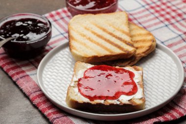 tost reçelli. karanlık bir arka plan üzerinde kırmızı reçel ile kızarmış gevrek ekmek. Kahvaltı.