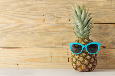 Doğal ahşap arka plan üzerinde güneş gözlüğü olgun meyve ananas. Yaz. metin için alan