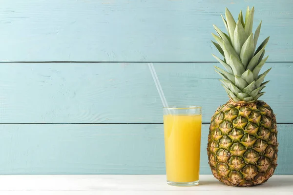 Ripe pineapple fruit and pineapple juice on a blue wooden background. place for text.