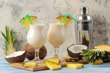 Kokteyl Pina Colada. Pina Colada hindistan cevizi sütü ve ananas suyu ile yaz alkollü kokteyl yakındaki. yaz içkisi. kokteyl hazırlığı. açık bir arka plan ve mavi bir masada.
