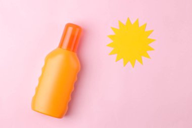 Parlak pembe bir arka plan üzerinde güneş kremi ve kağıt güneş. Yaz. Tatil. Güneş koruması. üst görünüm.
