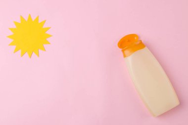Parlak pembe bir arka plan üzerinde güneş kremi ve kağıt güneş. Yaz. Tatil. Güneş koruması. üst görünüm.