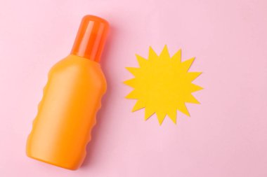 Parlak pembe bir arka plan üzerinde güneş kremi ve kağıt güneş. Yaz. Tatil. Güneş koruması. üst görünüm.