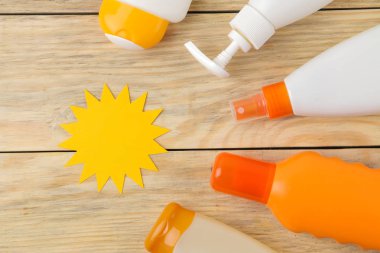 Güneş. çeşitli güneş kremleri ve doğal ahşap arka plan üzerinde kağıttan yapılmış güneş. Yaz. Tatil. Güneş koruması. üst görünüm.