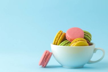 Macaronlar. bir fincan fransız çok renkli macaroons kek. parlak mavi arka plan üzerinde küçük fransız tatlı pasta. Tatlı. Tatlı.