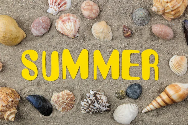 海の砂の上に紙の黄色い文字と貝殻の碑文夏 リラクゼーション トップビュー — ストック写真