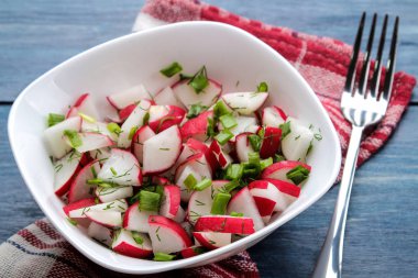 Mavi ahşap bir masada taze turp ve taze otlar Salatası. Bahar sebze salatası.