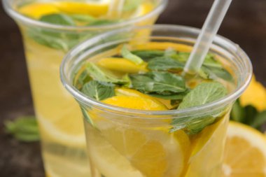 Kahverengi bir arka plan üzerinde plastik bardak nane ve limon ile ev yapımı limonata. Ferahlatıcı limonata içeceği. Close
