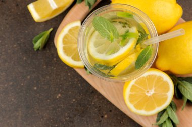Kahverengi bir arka plan üzerinde plastik bardak nane ve limon ile ev yapımı limonata. Ferahlatıcı limonata içeceği. üst görünüm