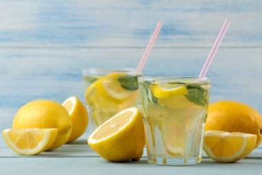 Mavi ahşap arka plan üzerinde plastik bardak nane ve limon ile ev yapımı limonata. Ferahlatıcı limonata içeceği.