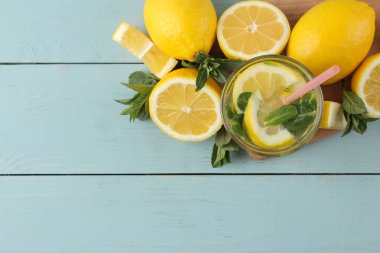 Mavi ahşap arka plan üzerinde plastik bardak nane ve limon ile ev yapımı limonata. Ferahlatıcı limonata içeceği. üst görünüm