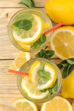 Doğal ahşap arka plan üzerinde plastik bardak nane ve limon ile ev yapımı limonata. Ferahlatıcı limonata içeceği. üst görünüm