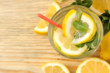 Doğal ahşap arka plan üzerinde plastik bardak nane ve limon ile ev yapımı limonata. Ferahlatıcı limonata içeceği. üst görünüm